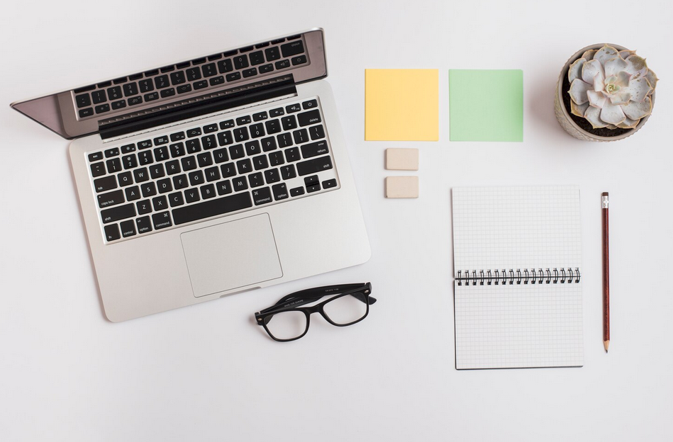 une page web s'affiche sur l'écran d'un ordinateur portable posé sur une table en bois. Un fauteuil, une table basse et une plante an arrière-plan.