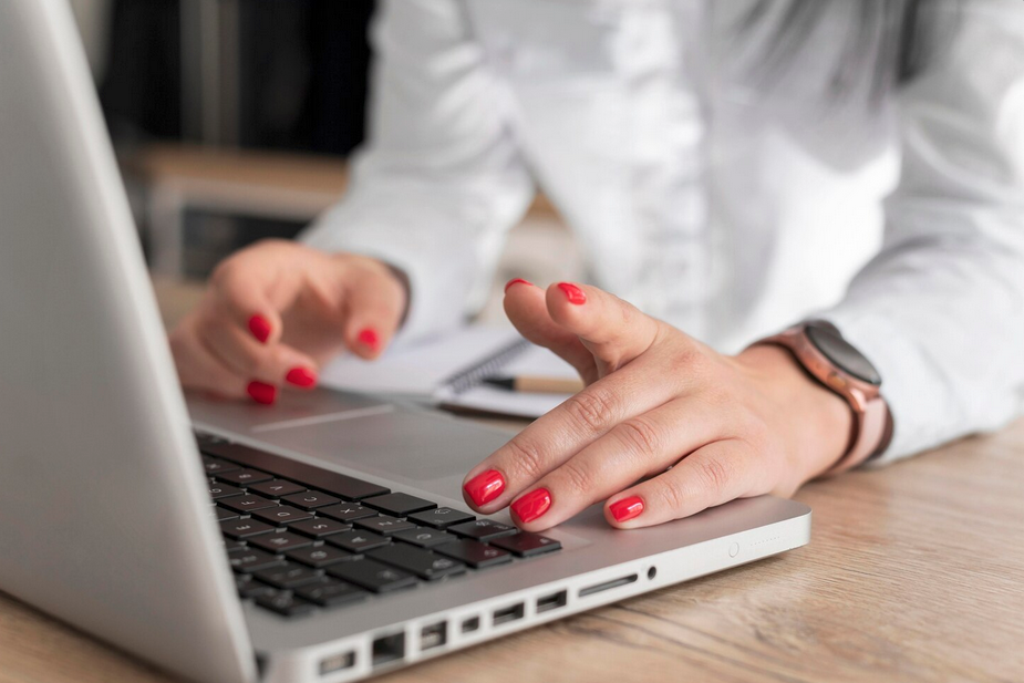une page web s'affiche sur l'écran d'un ordinateur portable posé sur une table en bois. Un fauteuil, une table basse et une plante an arrière-plan.